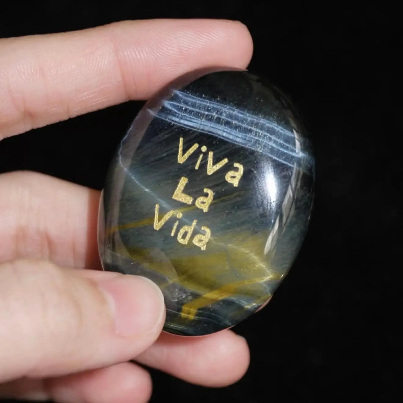 CIRCLEARA "Viva La Vida" etched Blue Tiger's Eye mineral. A tactile grounding tool for calm vitality and gratitude, showcasing natural hawk's eye chatoyancy and gold-leaf lettering.
