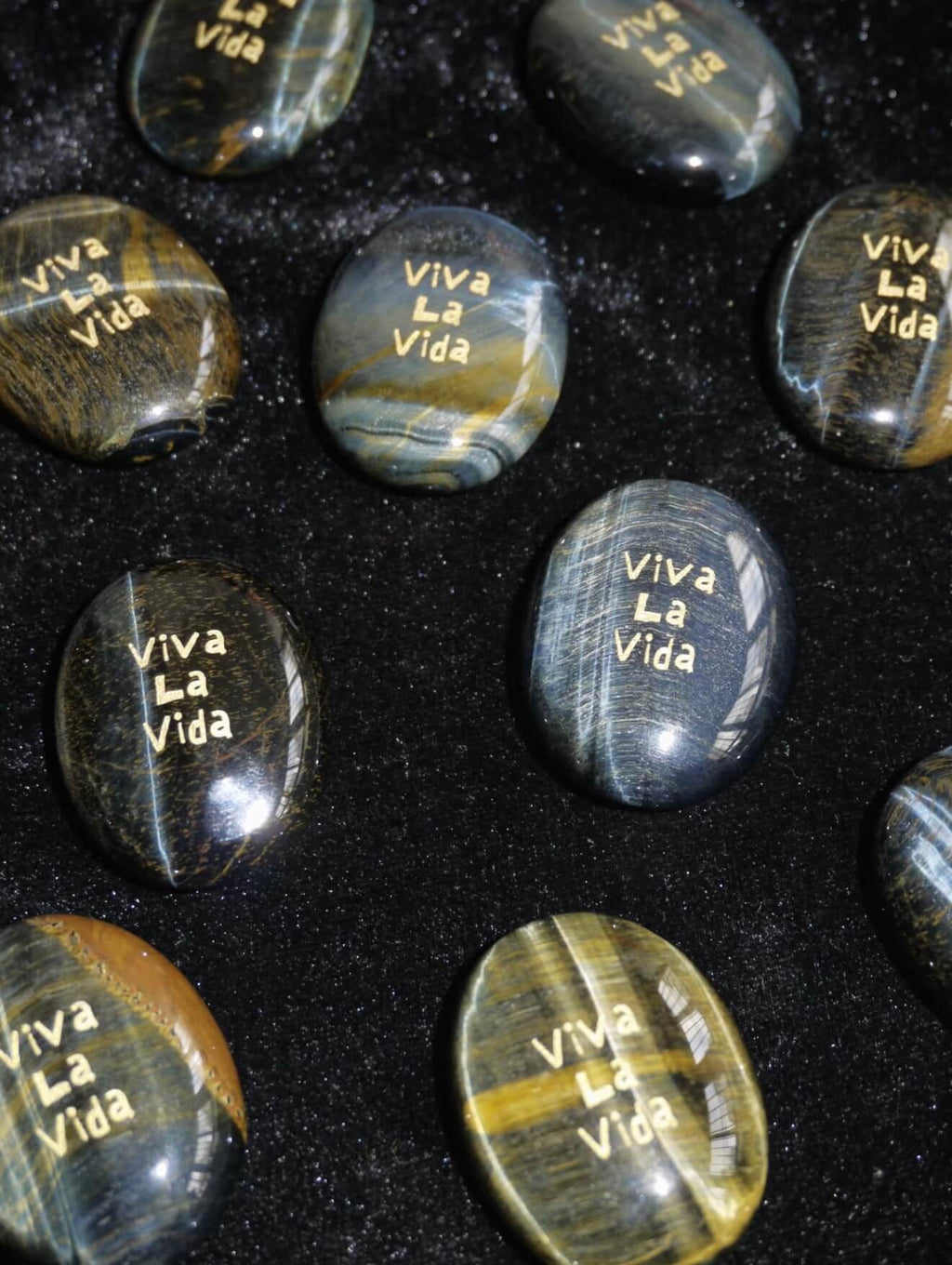 CIRCLEARA "Viva La Vida" etched Blue Tiger's Eye mineral. A tactile grounding tool for calm vitality and gratitude, showcasing natural hawk's eye chatoyancy and gold-leaf lettering.