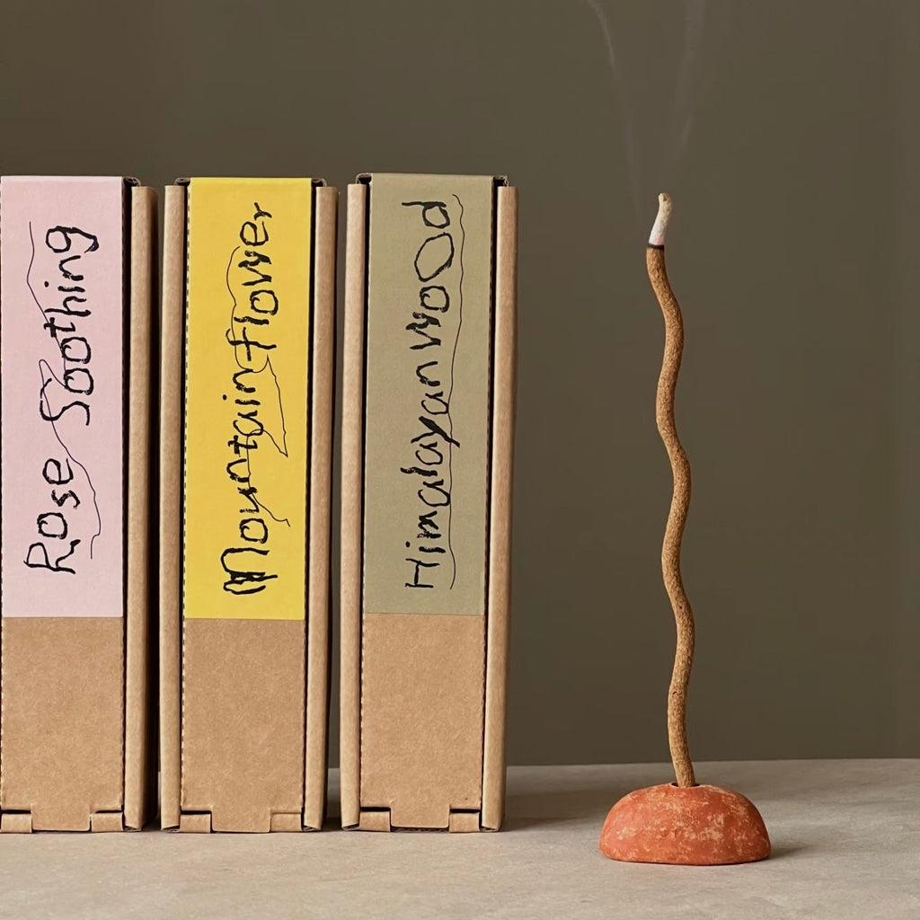 A single wavy botanical incense stick by CIRCLEARA in a red terracotta holder, representing a fluid energy reset.