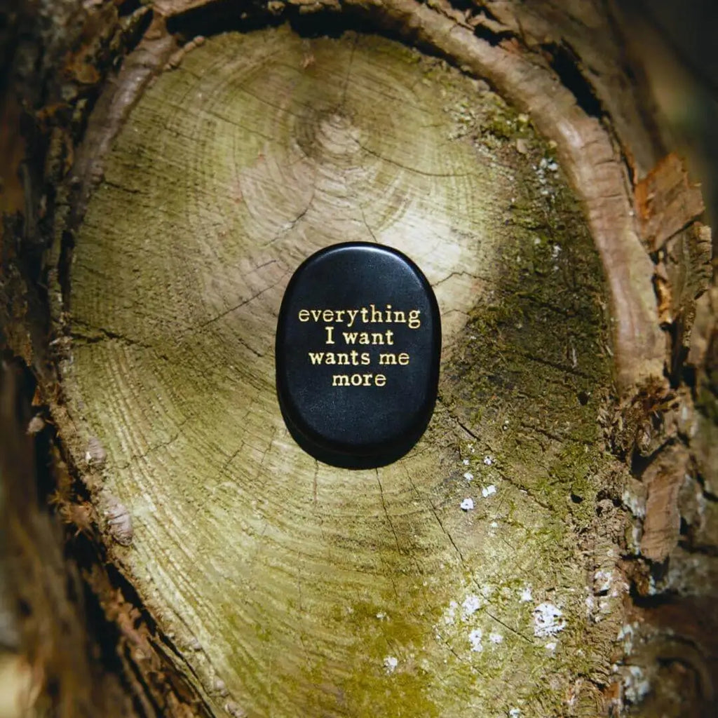 Black manifestation stone with gold engraving 'everything I want wants me more' for meditation and mindfulness