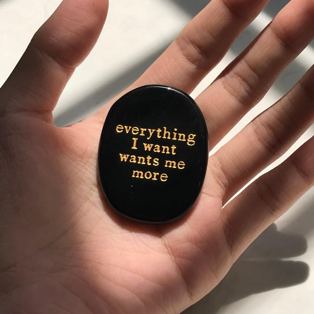 Black manifestation stone with gold engraving 'everything I want wants me more' for meditation and mindfulness