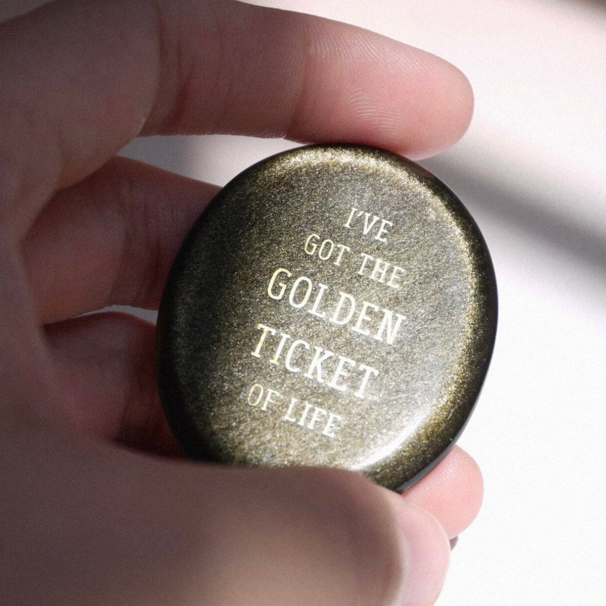 CIRCLEARA "Golden Ticket" manifest stone. Deep sheen mineral with gold-etched motivational mantra, designed as a tactile artifact for owning your abundance.