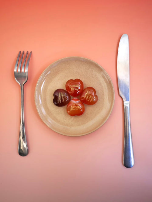 CIRCLEARA "Self-Happy" etched Carnelian heart. A tactile grounding mineral for emotional warmth and vitality, presented as a symbolic 'mental meal' on a dinner plate to represent self-care.