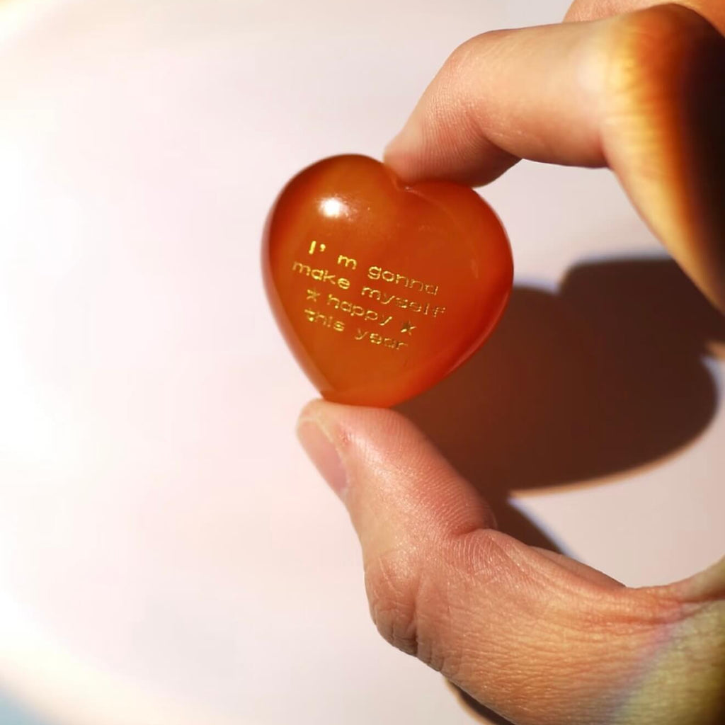CIRCLEARA "Self-Happy" etched Carnelian heart. A tactile grounding mineral for emotional warmth and vitality, presented as a symbolic 'mental meal' on a dinner plate to represent self-care.