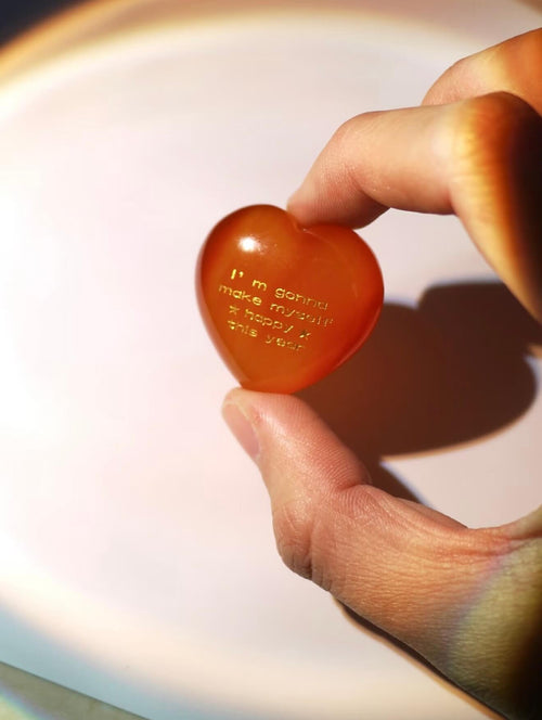 CIRCLEARA "Self-Happy" etched Carnelian heart. A tactile grounding mineral for emotional warmth and vitality, presented as a symbolic 'mental meal' on a dinner plate to represent self-care.