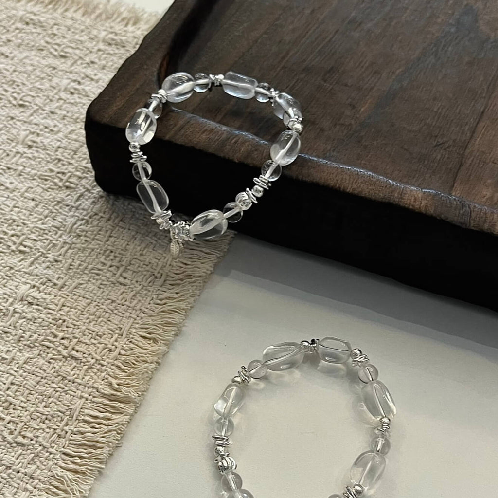 Handcrafted Clear Quartz grounding bracelet featuring smooth, transparent sugar-bean cut crystal beads and 925 sterling silver accents, laid on a clean aesthetic surface.