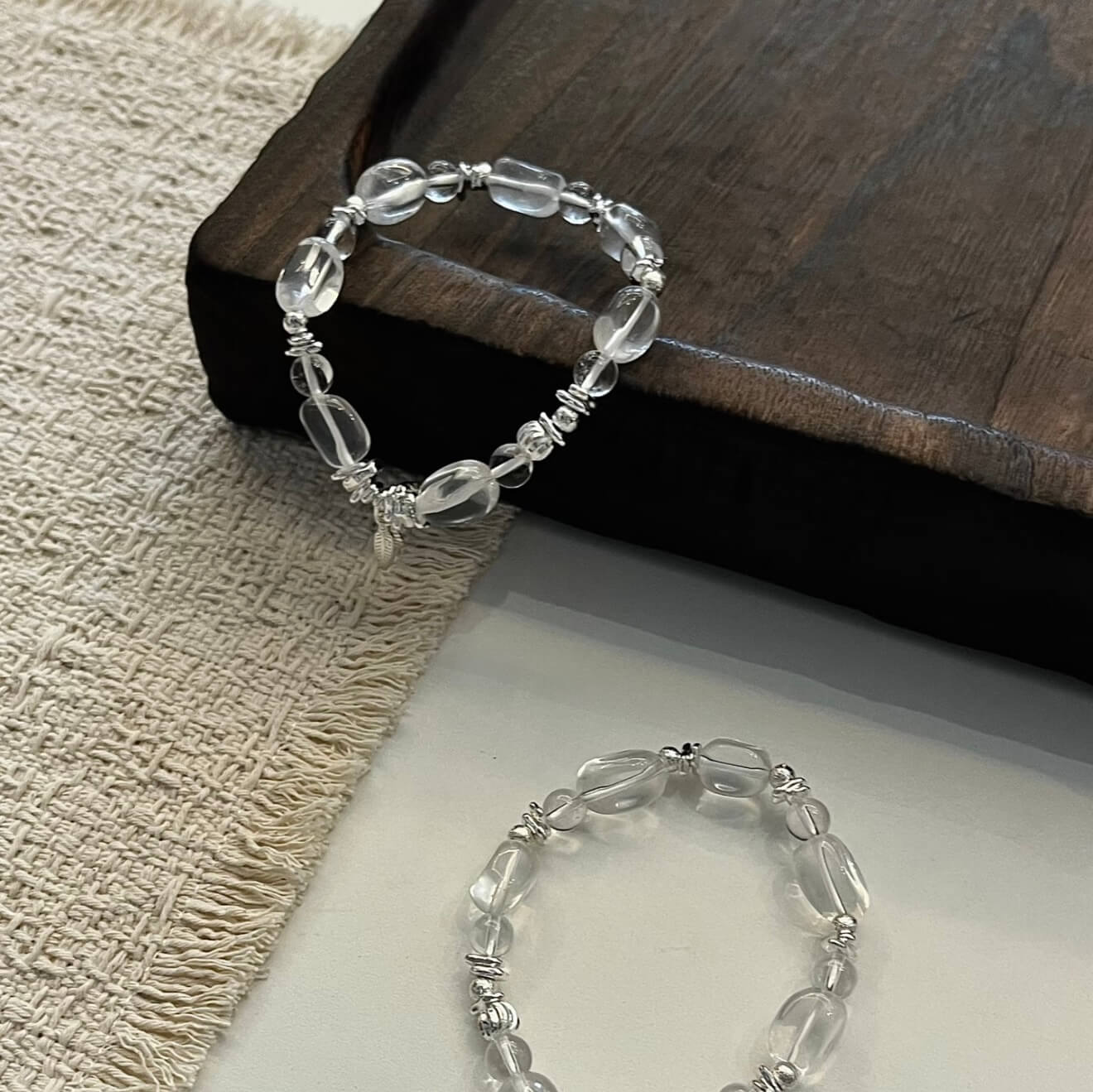 Handcrafted Clear Quartz grounding bracelet featuring smooth, transparent sugar-bean cut crystal beads and 925 sterling silver accents, laid on a clean aesthetic surface.