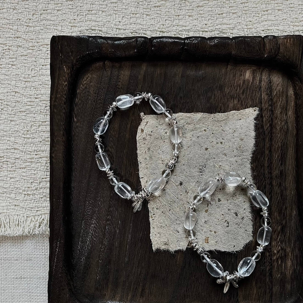 Handcrafted Clear Quartz grounding bracelet featuring smooth, transparent sugar-bean cut crystal beads and 925 sterling silver accents, laid on a clean aesthetic surface.