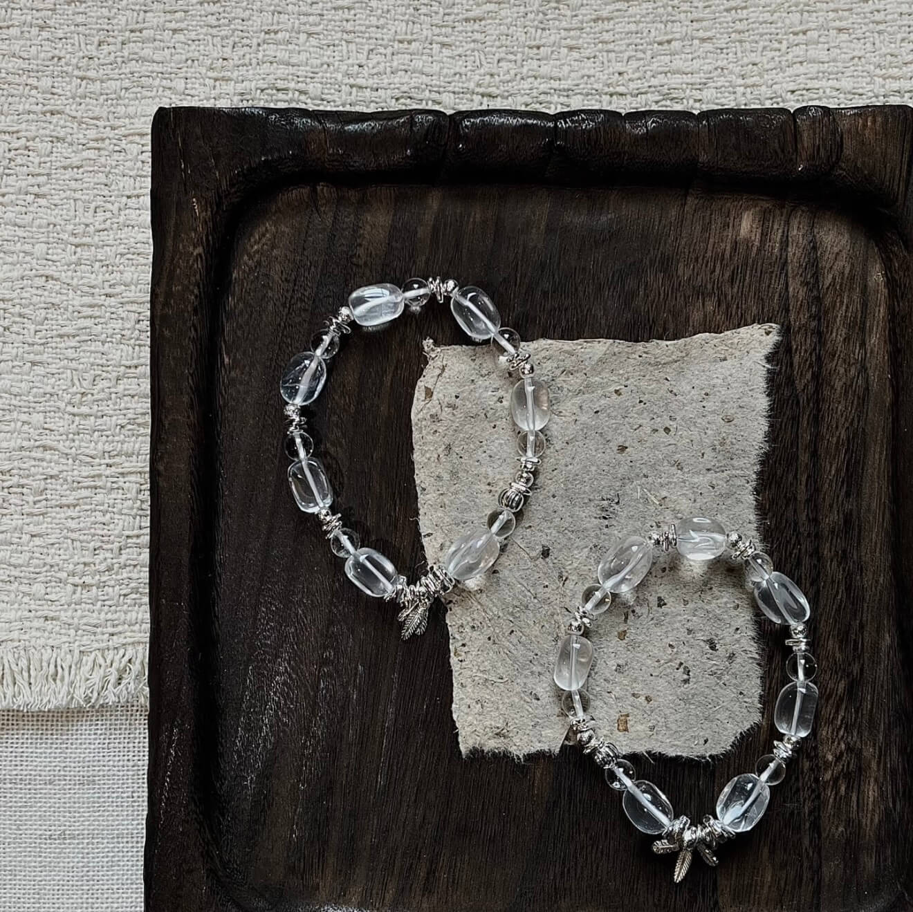 Handcrafted Clear Quartz grounding bracelet featuring smooth, transparent sugar-bean cut crystal beads and 925 sterling silver accents, laid on a clean aesthetic surface.