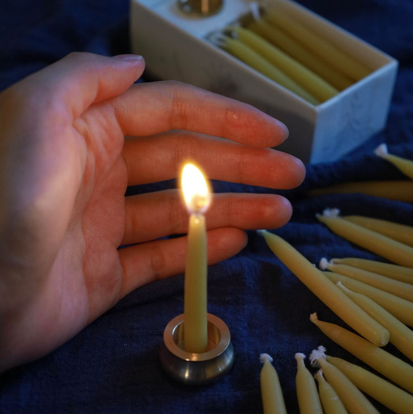 Handcrafted 20-minute golden beeswax meditation candle set by CIRCLEARA, featuring a lit petite taper candle in a solid brass holder and a minimalist ritual gift box on a dark textured surface.