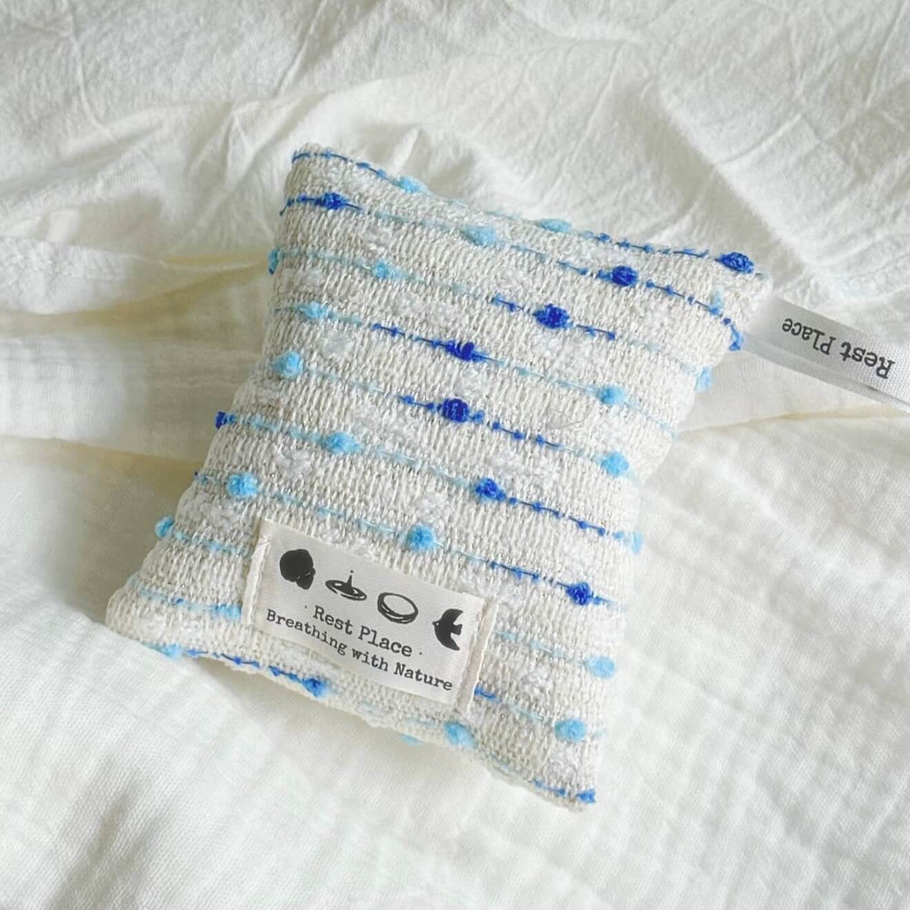 A handcrafted blue and white woven herbal sachet by CIRCLEARA, symbolizing a cool, flowing stream of emotional intuition.
