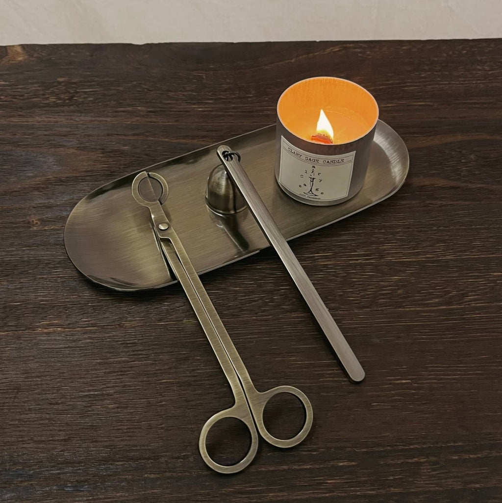A set of CIRCLEARA candle care ritual tools in five metallic finishes, showing the weighted wick trimmer and bell snuffer in high-detail electroplating.