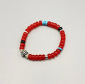 Handcrafted Crimson Compass men's grounding bracelet with vibrant red ceramic glaze beads, rugged raw turquoise stone fragments, and a metallic silver cross on a clean aesthetic background.