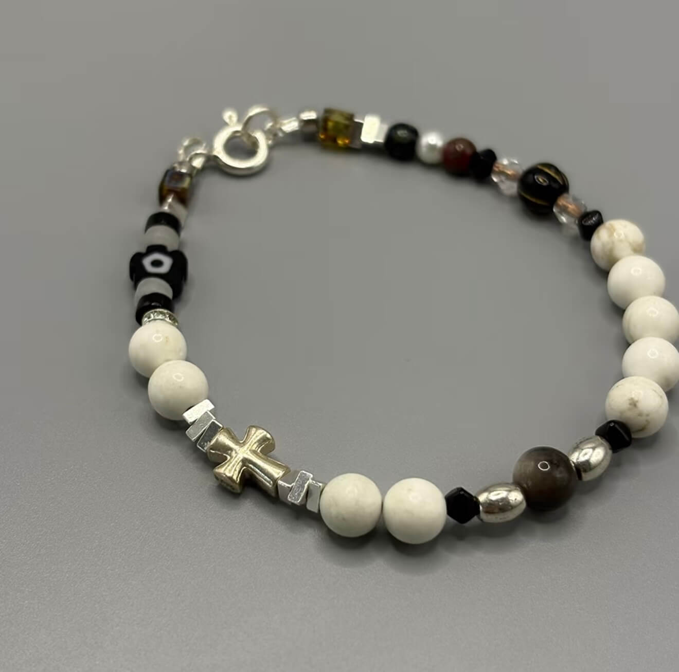 CIRCLEARA Monochrome Muse Bracelet: White howlite beads, silver sheen obsidian, and a sterling silver cross. A luxury minimalist grounding tool for focus and calm.