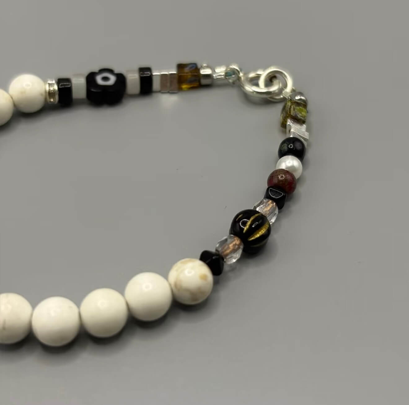 CIRCLEARA Monochrome Muse Bracelet: White howlite beads, silver sheen obsidian, and a sterling silver cross. A luxury minimalist grounding tool for focus and calm.