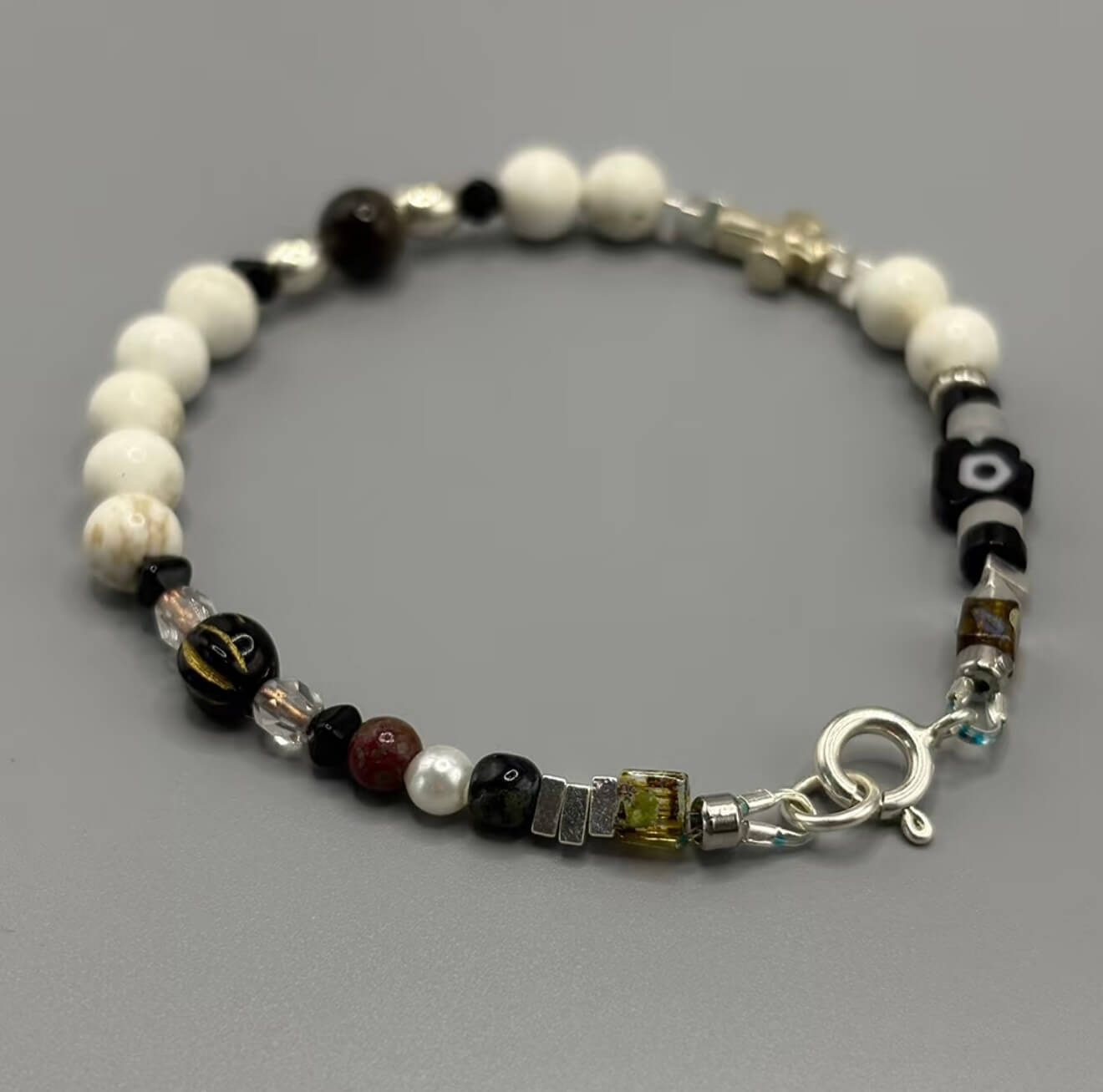 CIRCLEARA Monochrome Muse Bracelet: White howlite beads, silver sheen obsidian, and a sterling silver cross. A luxury minimalist grounding tool for focus and calm.