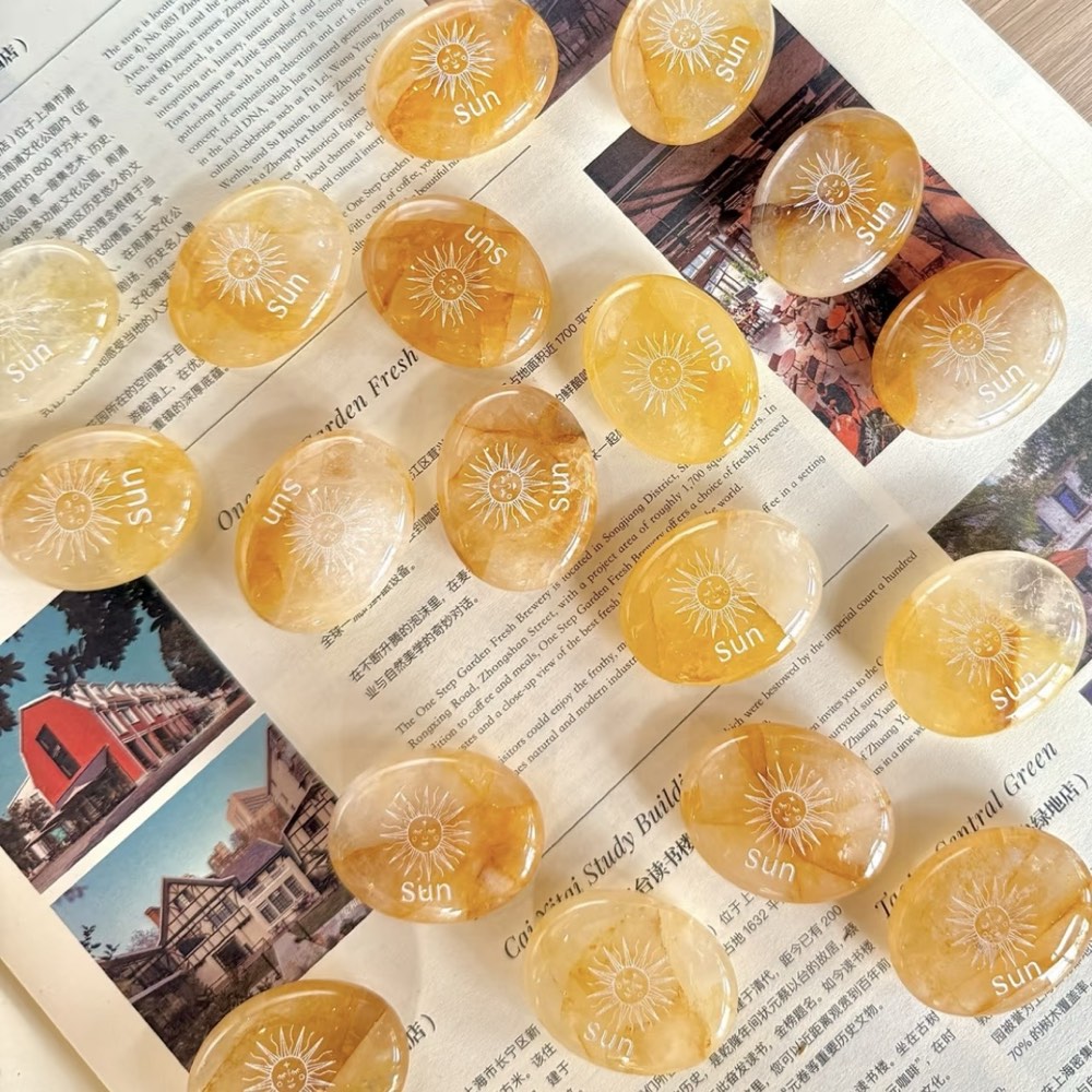 Handcrafted natural golden hematoid yellow quartz palm stones engraved with silver text 'SUN' and a star by CIRCLEARA, displaying vibrant internal inclusions.