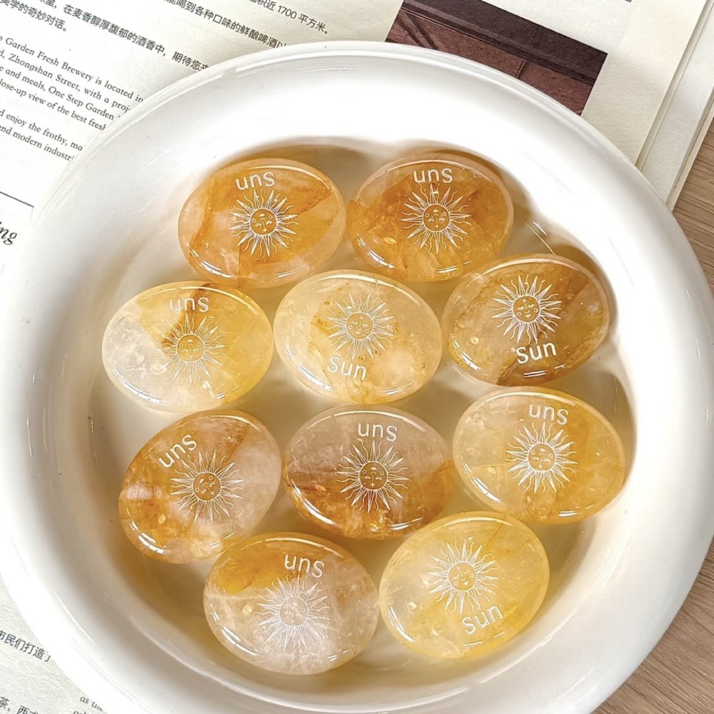Handcrafted natural golden hematoid yellow quartz palm stones engraved with silver text 'SUN' and a star by CIRCLEARA, displaying vibrant internal inclusions.