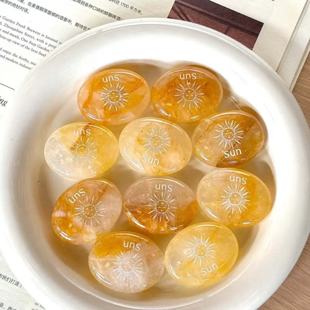 Handcrafted natural golden hematoid yellow quartz palm stones engraved with silver text 'SUN' and a star by CIRCLEARA, displaying vibrant internal inclusions.