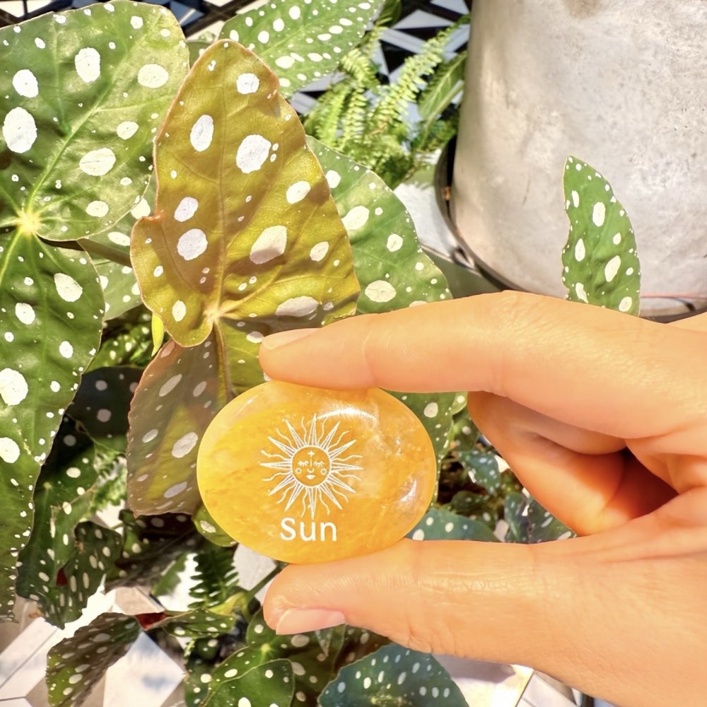 Handcrafted natural golden hematoid yellow quartz palm stones engraved with silver text 'SUN' and a star by CIRCLEARA, displaying vibrant internal inclusions.