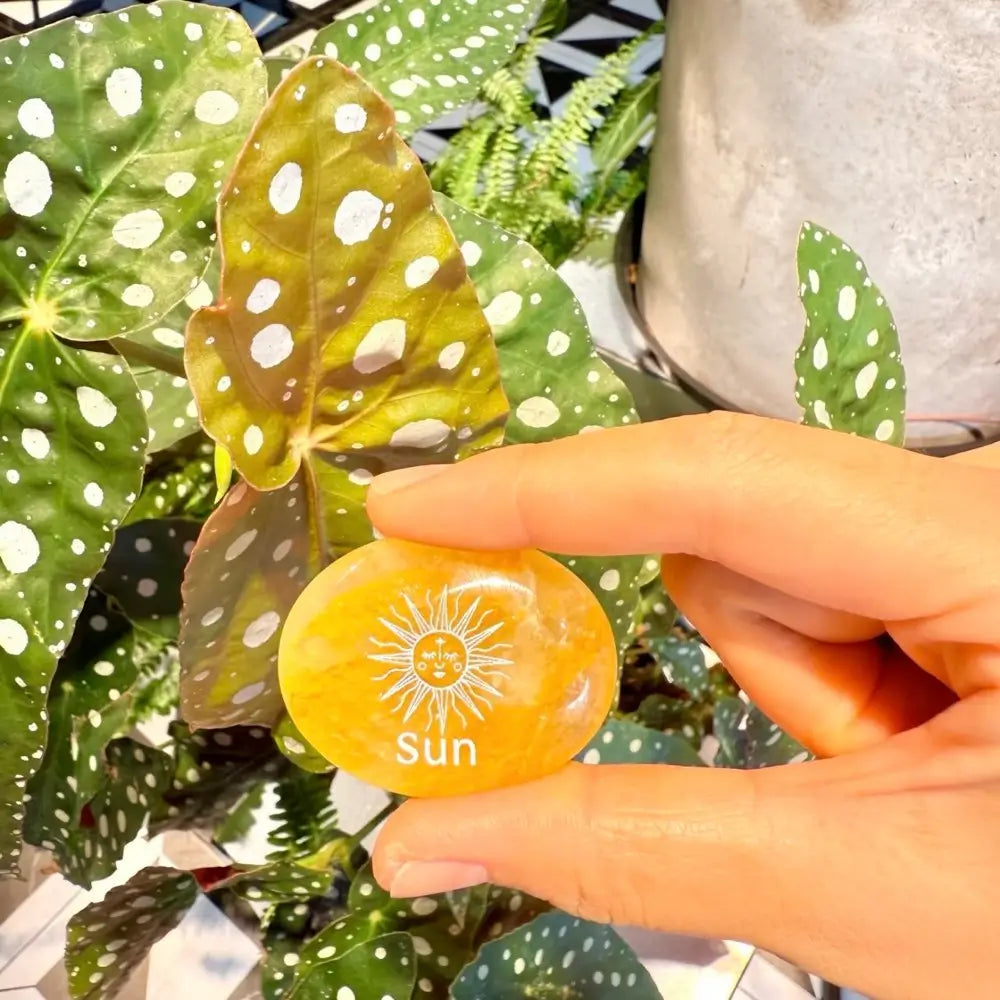 Handcrafted natural golden hematoid yellow quartz palm stones engraved with silver text 'SUN' and a star by CIRCLEARA, displaying vibrant internal inclusions.