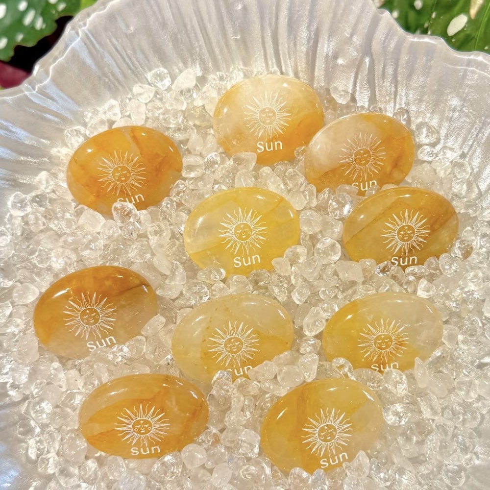 Handcrafted natural golden hematoid yellow quartz palm stones engraved with silver text 'SUN' and a star by CIRCLEARA, displaying vibrant internal inclusions.