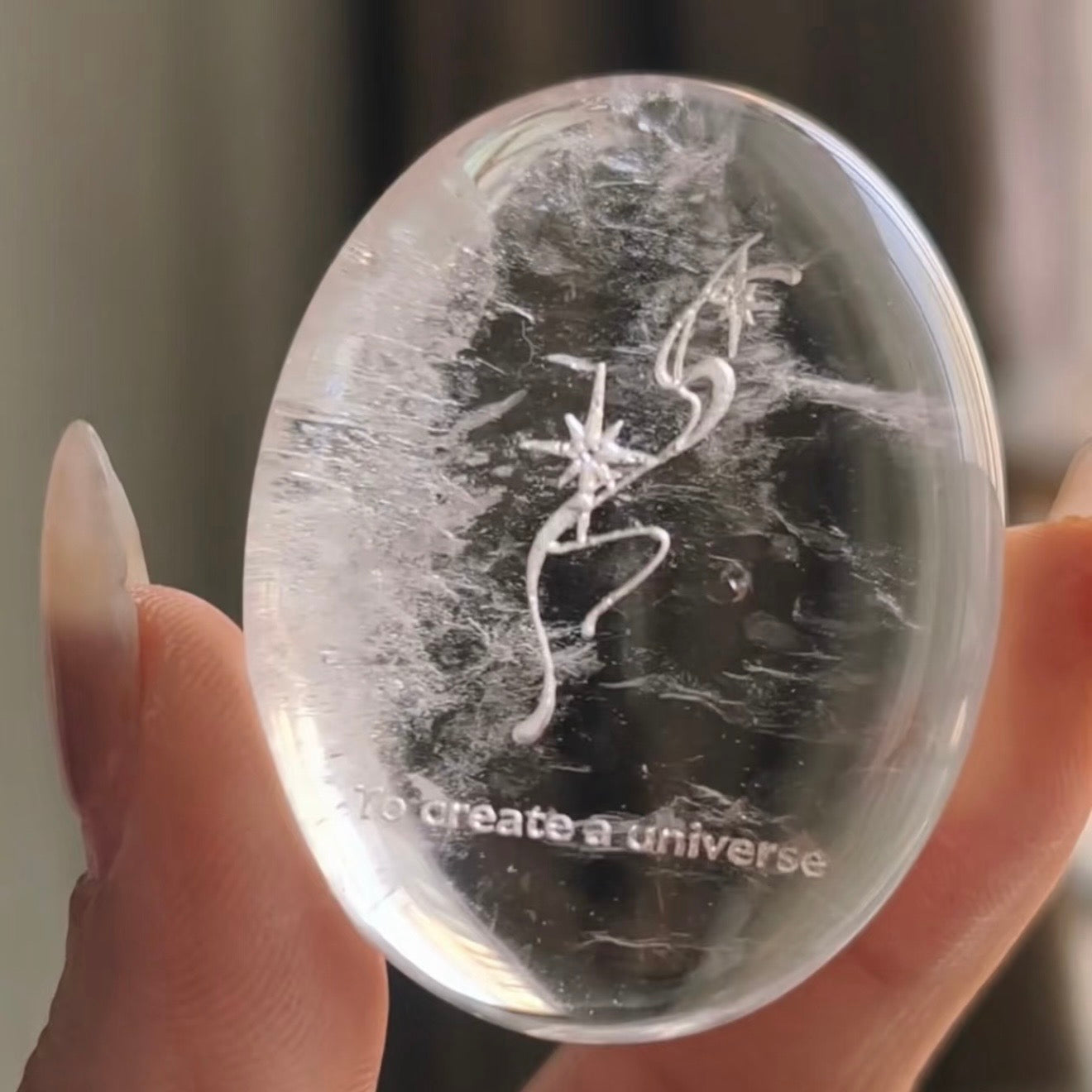 Handcrafted natural clear quartz meditation stone engraved with silver 'To create a universe' and starburst symbols by CIRCLEARA, showing beautiful internal crystal veils.