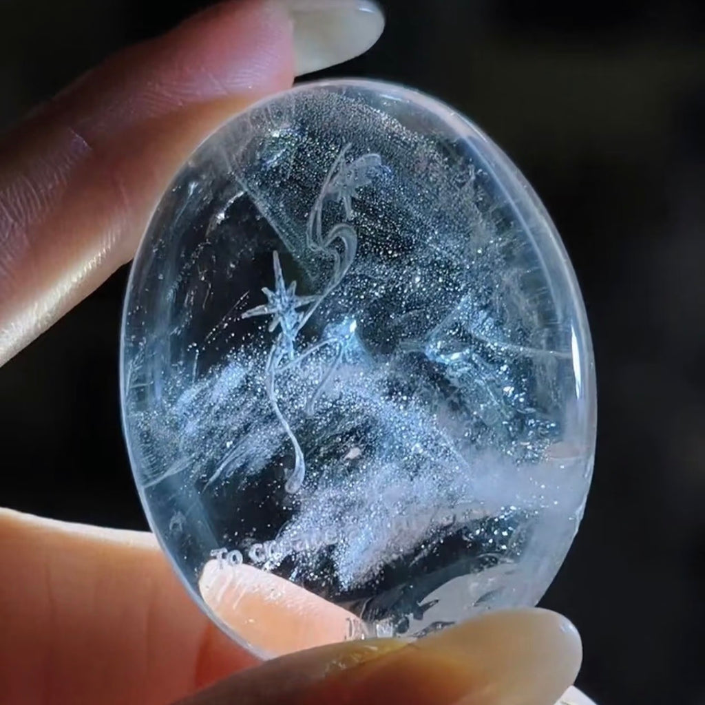 Handcrafted natural clear quartz meditation stone engraved with silver 'To create a universe' and starburst symbols by CIRCLEARA, showing beautiful internal crystal veils.