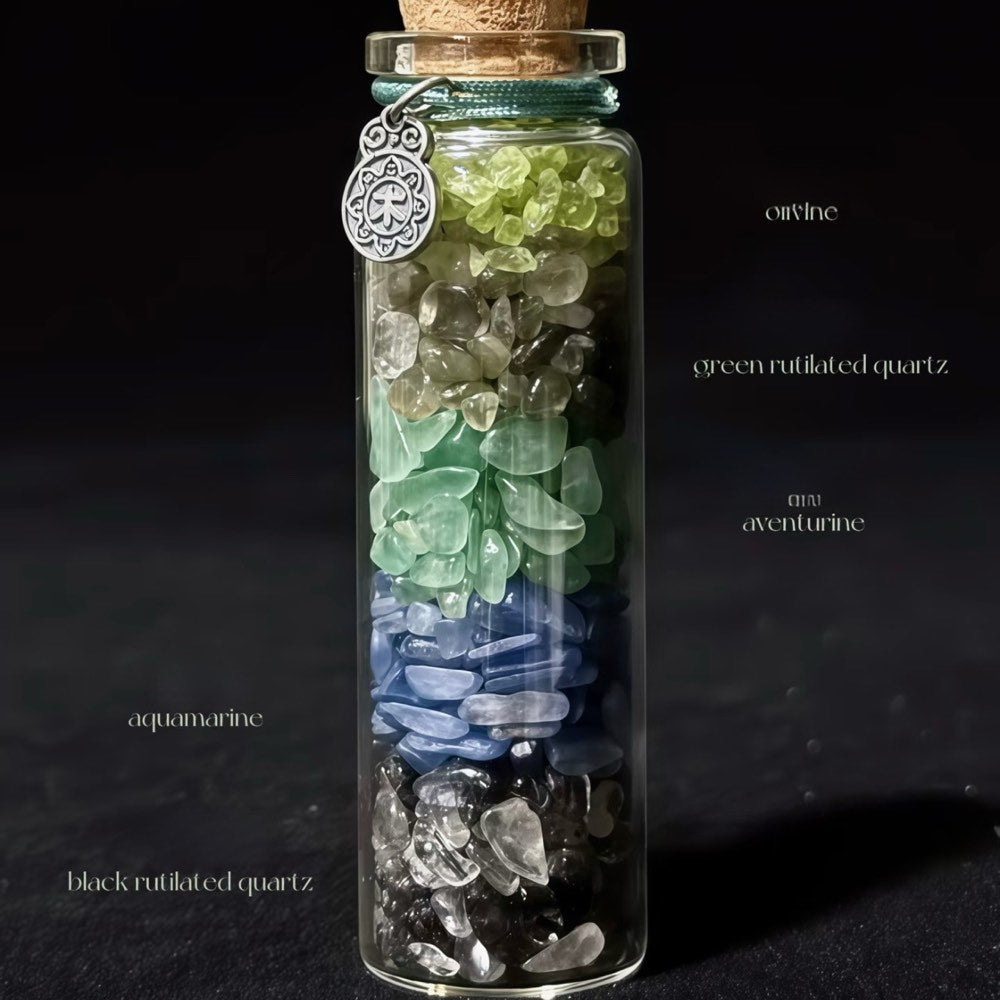 Handcrafted 7x2.2cm glass crystal ritual bottle filled with layered raw mineral chips and a metallic charm by CIRCLEARA.