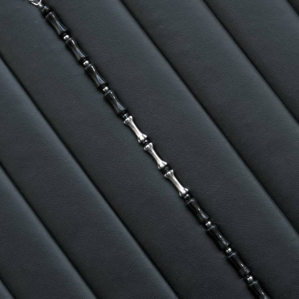 A vertical, high-contrast detail shot of the CIRCLEARA Backbone bracelet, highlighting the alternating sequence of glossy, curved black onyx cylinders and hand-contoured 925 sterling silver spinal joints.