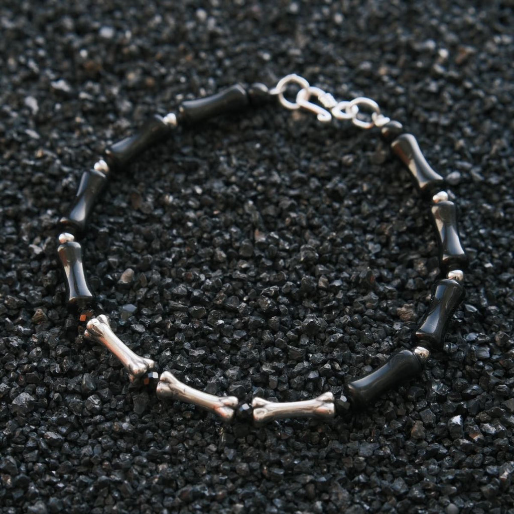 A vertical, high-contrast detail shot of the CIRCLEARA Backbone bracelet, highlighting the alternating sequence of glossy, curved black onyx cylinders and hand-contoured 925 sterling silver spinal joints.