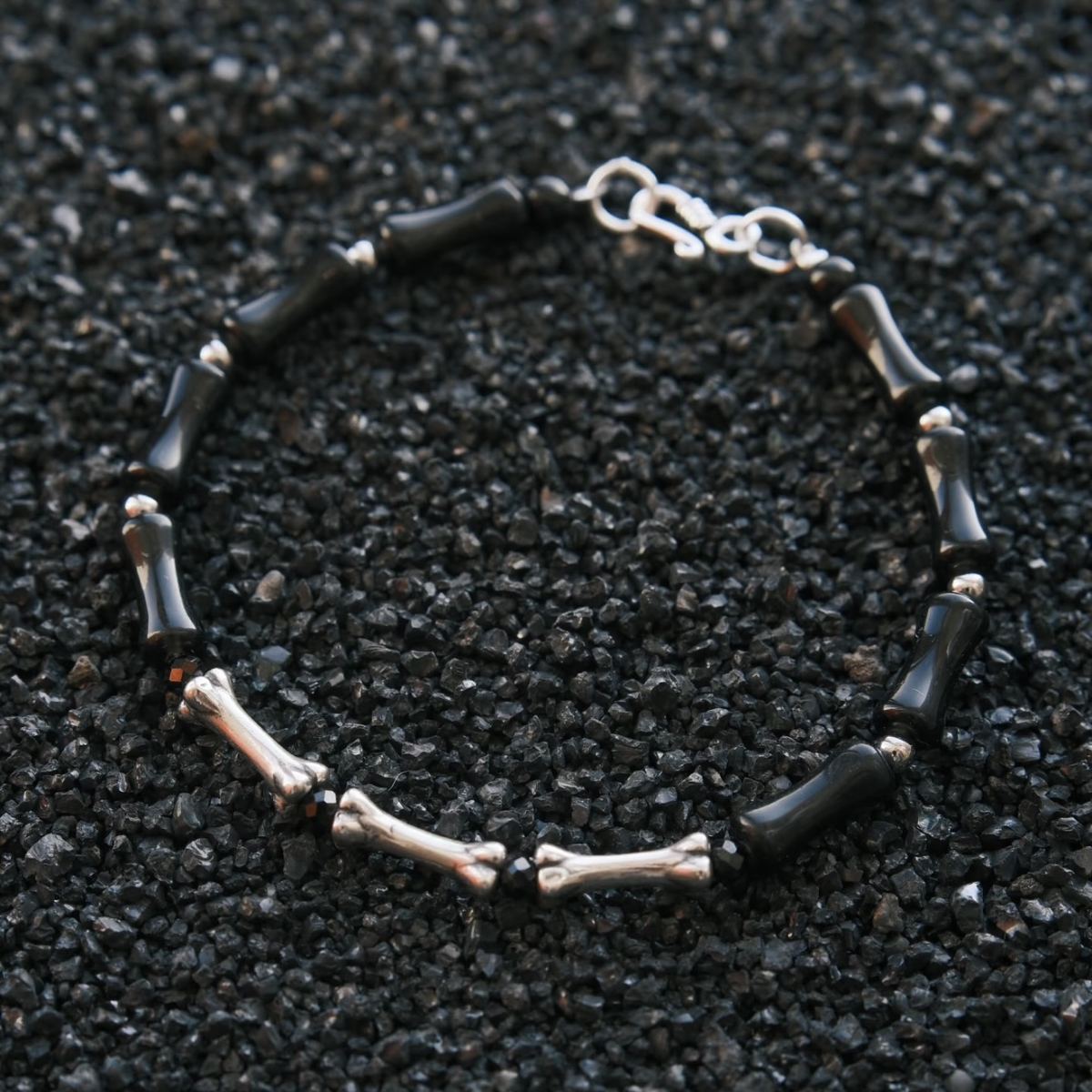 A vertical, high-contrast detail shot of the CIRCLEARA Backbone bracelet, highlighting the alternating sequence of glossy, curved black onyx cylinders and hand-contoured 925 sterling silver spinal joints.