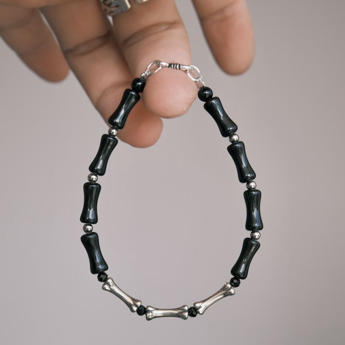 A vertical, high-contrast detail shot of the CIRCLEARA Backbone bracelet, highlighting the alternating sequence of glossy, curved black onyx cylinders and hand-contoured 925 sterling silver spinal joints.