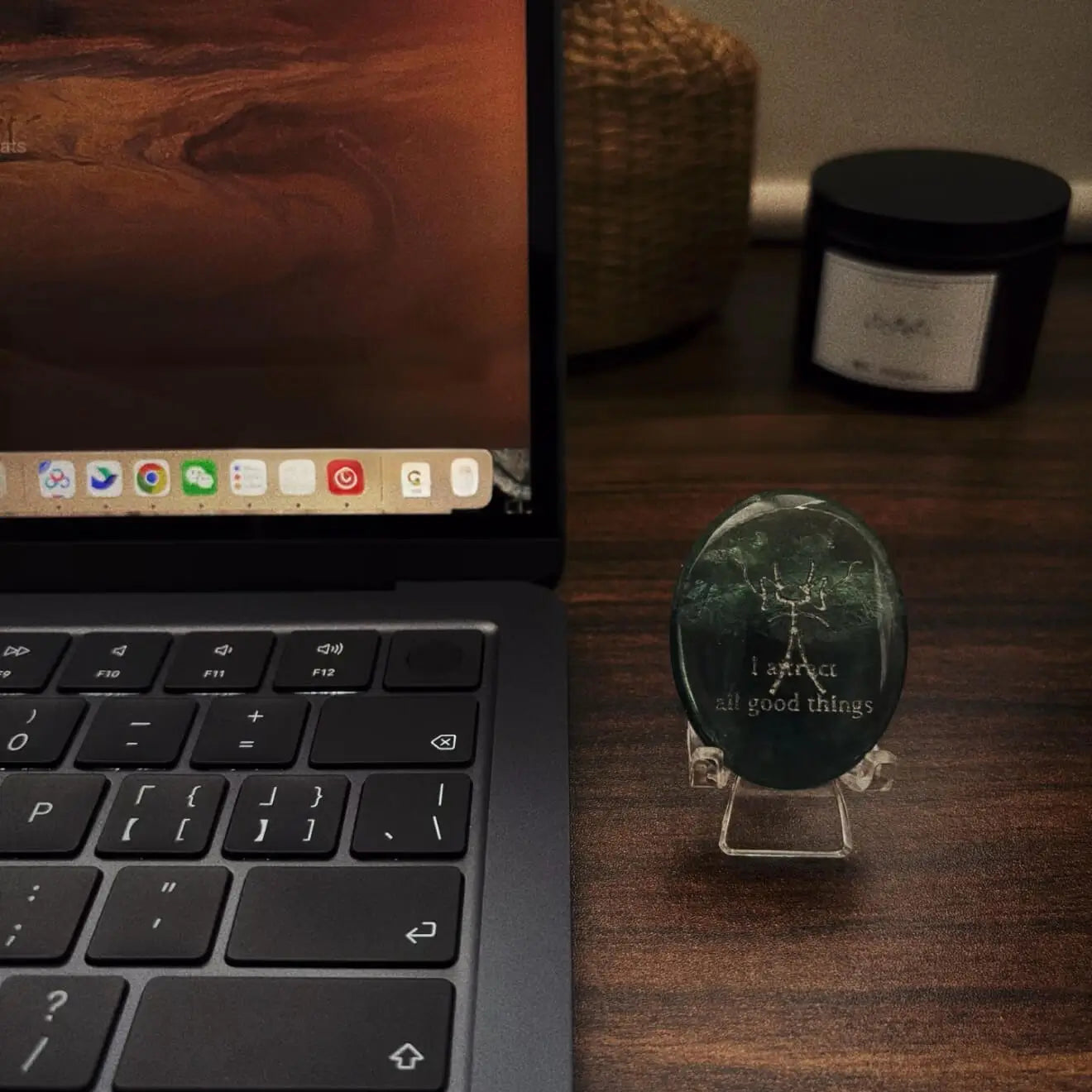 A front-facing detailed shot of the translucent green fluorite CIRCLEARA palm stone resting on its complimentary clear minimalist stand, revealing the precise Dongba pictograph and the etched phrase "I attract all good things."